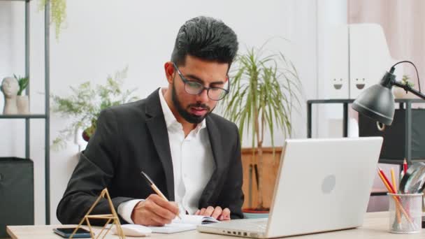 Modern Ofis Çalışma Masasında Çalışan Ciddi Hintli Adamı Notlarını Deftere — Stok video