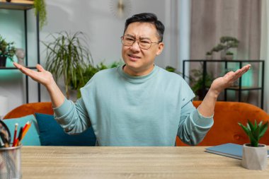 Ne diyecegimi bilmiyorum. Kafası karışmış Asyalı Japon adam belirsiz bir soru hakkında utanmış, kuşkuları var, hiçbir fikri yok, bilgisiz ve kararsız. Orta yaşlı Çinli bir adam kanepede oturuyor.