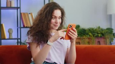 Mutlu genç bir kadın cep telefonu daktilosu kullanıyor ve 