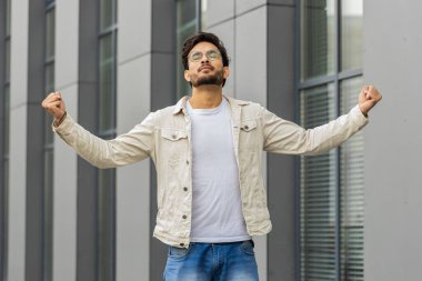 Genç Hintli adam derin bir nefes alıyor, dinleniyor, dinleniyor, meditasyon yapıyor, dışarıda sakinleşiyor. Arap Hindu adam şehir merkezinde mutlu bir gün geçiriyor. İş adamları