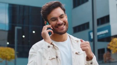 Telefon, iyi haber, dedikodu. Akıllı telefondan hoş sohbetler yapan mutlu Hintli adam dışarıda arkadaşlarıyla konuşmaktan zevk alıyor. Şehir caddesinde duran Arap Hindu adam. Kasaba yaşam tarzları
