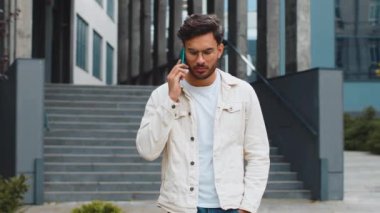 Genç Hintli bir adam dışarıda akıllı telefonla konuşuyor. Arap Hindu adam şehir merkezinde beklenmedik bir şekilde dedikodu yapıyor. İş adamları