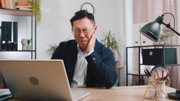 Проблемы Зубами Азиатский Бизнесмен Работающий Офисе Трогает Щеку Закрывает Глаза — стоковое видео