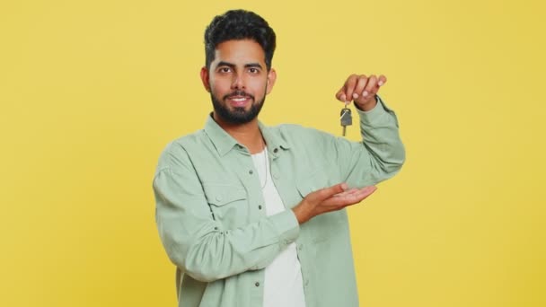 インドの若い男不動産エージェントは 新しい家のアパートの鍵を示す手を持ち上げ 不動産を購入または賃貸 住宅ローン イエロースタジオで孤立したアラビアの男 — ストック動画