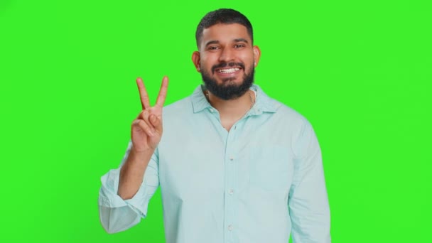 快乐的印度年轻人展示出胜利的迹象 希望成功和胜利 做一个和平的姿态 带着友善乐观的微笑 庆祝胜利 用绿色彩色键背景隔离的阿拉伯男人 — 图库视频影像