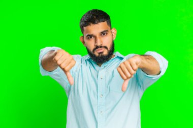 Hoşlanmamak. Mutsuz Hintli adam, hoşnutsuzluğunu, memnuniyetsizliğini ve olumsuz tepkilerini belirterek işaret gösteriyor. Çekici sakallı adam kapalı mekanda, krom anahtar arka planda izole edilmiş.