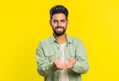 Bedava hediyeler ve hediyeler. Hintli adam ellerini açıyor, heyecan, hazırlama sürprizi, aşk duygularını paylaşıyor, tebrik ediyor, bağış yapıyor. Sarı stüdyo arka planında izole edilmiş bir Arap.