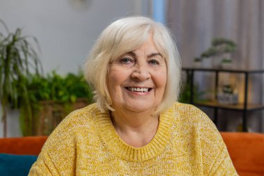 Mutlu yaşlı bir kadının yakın plan portresi mutlu mutlu bir surat ifadesinin dinlenme hayalleri tatmin edici bir konsept iyi haberler evde zaferi kutlar. Yaşlı olgun büyükanne masada oturuyor.