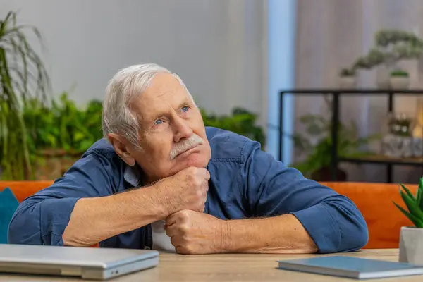 Portrait of sad stressed senior old grandfather man sits at home looks pensive thinks over life concerns, suffers from unfair situation. Problem crisis depression feeling bad sick ill annoyed burnout