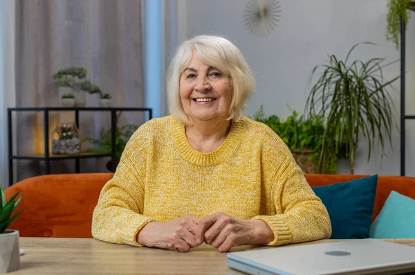 Portrait of happy calm senior old woman smiling glad expression looking dreaming resting relaxation feel satisfied concept good news celebrate win at home indoors. Elderly grandmother sits at table