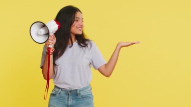 Hintli genç kadın megafonla konuşuyor, haberleri duyuruyor, reklam indirimlerini yüksek sesle duyuruyor, konuşma yapmak için hoparlör kullanıyor. Mutlu Arap kız stüdyo sarı arka planda izole