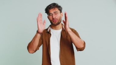 Duymak ve dinlemek istemiyorum. Sinirli sinirli Hintli genç adam hayır diyerek kulaklarını kapatıyor, nahoş sesleri duymazdan gelerek tavsiyelerden kaçıyor. Gri arka planda izole Arap adam