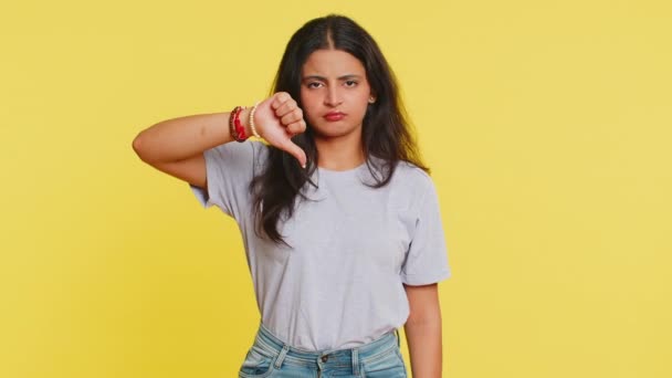 気に入らない 不満なインドの女性は サインジェスチャーの下に親指を示し 不承認 不満の否定的なフィードバックを表現します 黄色の背景に隔離された屋内で魅力的なヒンドゥーガール — ストック動画