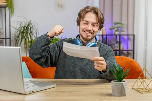 Happy Caucasian man open envelope letter, reading it. Career growth advance promotion, bank loan approve, successful admission to university monetary award invitation great news, lottery game win