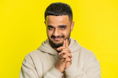 Sinsi, kurnaz, hilekar, şakacı, sinsi, sinsi yüzlü, sinsi, sinsi, sinsi, sinsi, sinsi, sinsi bir Hintli. Arap Hindu adam sarı arka planda kapalı alanda izole edilmiş.