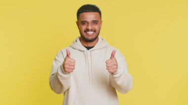 Gibi. Hintli adam bir şeyi onaylıyor ya da olumlu cevap veriyor reklamlar iyi fikir geri bildirimlerini seviyor, başarı zaferini kutluyor. Stüdyo sarı arka planda izole edilmiş.