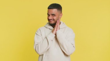 Sinsi kurnaz Hintli genç adam hileli yüz hareketleriyle ve şeytani planlarıyla sinsi kötü adam fikrini, hilekarlığını, şakalarını, şakalarını düşünüyor. Sarı stüdyo arka planında izole edilmiş Arap Hindu adam.