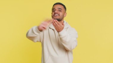 Hintli adam savurma israfını gösteriyor paylaşma parası, daha fazla bahşiş, büyük kar, piyango ikramiyesi kazanma, başarılı alışveriş ödeme nakiti. Sarı arka planda izole edilmiş Arap Hindu adam.