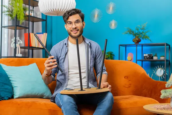 Happy Indian Arabian man finishing assembling furniture at home. Successful table desk collect, repair fixing. Arabian guy after moving into new apartment. Advertisement of a furniture store. Mortgage