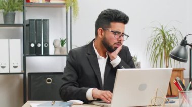 Diş sorunları. Ofiste çalışan Hintli işadamı yanaklarına dokunarak, korkunç bir ifade ile gözlerini kapatarak diş ağrısı, hassas dişler, çürükler yüzünden acı çekiyor. Resmi takım elbiseli erkek Hindu.