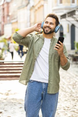 Kablosuz kulaklıklar takmış, açık havada dans eden enerjik disko rock n roll müziği dinleyen mutlu, gevşemiş Kafkas genci. Şehirdeki Sunshine Sokağı 'nda duran adam. Dikey