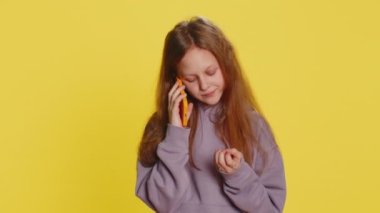 Çocukluk çağındaki ilgisiz çocuk, akıllı telefonda can sıkıcı konuşmalar yapıyor. Çocuklar arkadaşlarıyla cep telefonu konuşmaktan, sarı arka planda çevrimiçi konuşmaktan yoruldular.