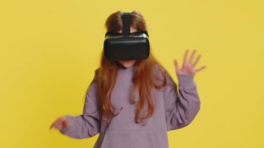 Kulaklık takıp simülasyon oyunu oynayan heyecanlı çocukluk çağındaki çocuk. Sanal gerçeklik 3D 360 videosu izliyoruz. VR gözlüklü çocuklar sarı arka planda izole edilmiş. Gelecek teknolojisi