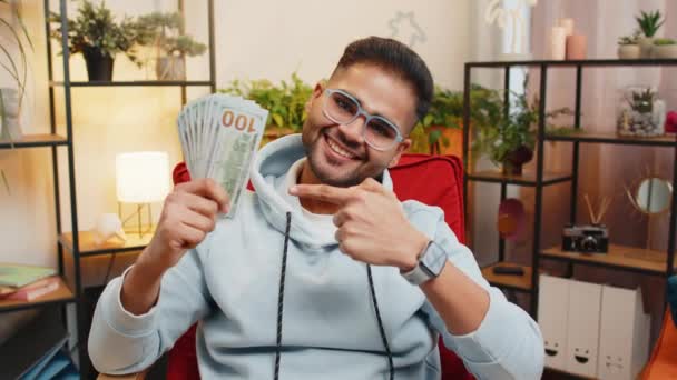 ハッピーリッチなビジネスインドの男は 高い利益で応援お金を数え 宝くじのゲームの勝利を祝い 富の収入の給与に満足し 自宅でドル現金を指摘する — ストック動画