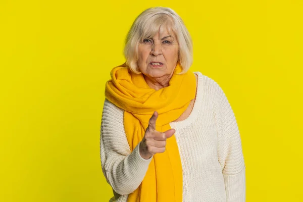 Quarrel. Displeased aggressive unhappy senior old woman gesturing hands with irritation and displeasure, blaming scolding for failure asking why this happened. Elderly grandmother on yellow background