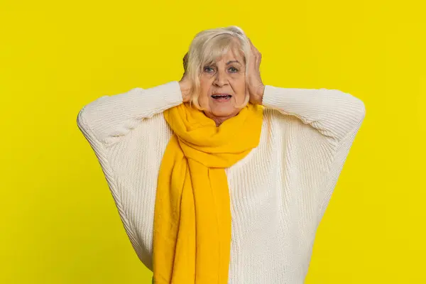 Dont want to hear and listen. Frustrated annoyed irritated senior old woman covering ears gesturing no avoiding advice ignoring unpleasant noise loud voices. Grandmother isolated on yellow background