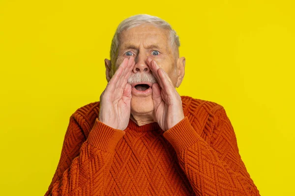 Keep my secrets, silence. Senior old man whisper news rumors holding hands near mouth, share gossip, quiet. Elderly grandfather pensioner telling interesting confidential story on yellow background