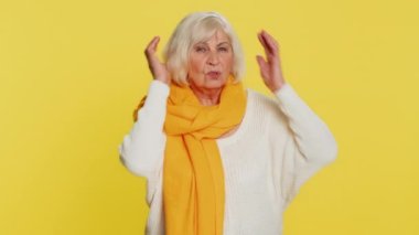 Duymak ve dinlemek istemiyorum. Sinirli, sinirli, yaşlı bir kadın kulaklarını kapatıyor. Tavsiye vermekten kaçınmıyor, gürültülü sesleri görmezden geliyor. Büyükannem sarı arka planda izole edilmiş.