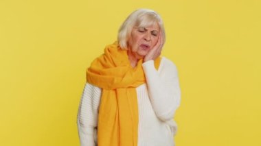 Diş sorunları. Yaşlı bir kadın yanağa dokunuyor, gözleri korkunç bir ifadeyle kapanıyor diş ağrısı, hassas dişler, çürükler yüzünden acı çekiyor. Sarı arka planda yaşlı bir büyükanne.