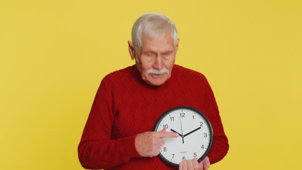 这是你的时间 年长的老人在墙上的时钟上显示时间 竖起大拇指批准指尖相机 截止日期 上了年纪的祖父因黄种原因被隔离 — 图库视频影像