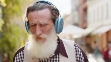 Kablosuz kulaklıklar takmış, dışarıda dans eden enerjik disko rock 'n roll müziği dinleyen mutlu, aşırı neşeli yaşlı yaşlı bir adam. Yaşlı büyükbaba şehir caddesinde yürüyor