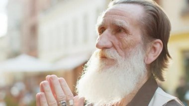 Sakallı dinin portresi. Son sınıf öğrencisi, Tanrı 'ya gözleri kapalı dua ediyor. Dışarıda kutsama, yardım ve af diliyor. Yaşlı büyükbaba, güneşli şehir sokağında şans diliyor.