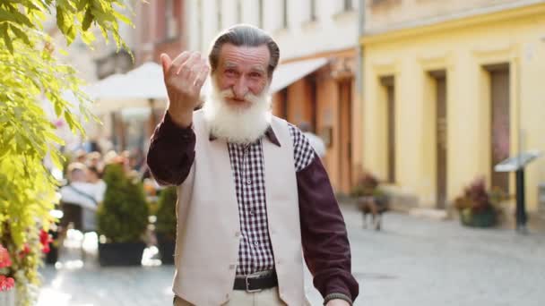 Skäggig Senior Man Ler Vänligt Mot Kameran Viftar Med Händerna — Stockvideo