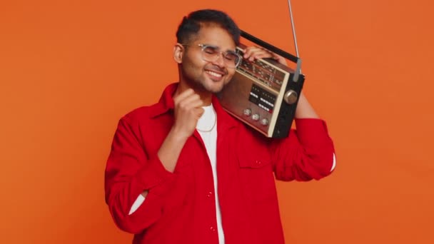 レトロテープレコードプレーヤーを使用してレトロテープレコードプレーヤー ディスコお気に入りのトラックを踊る 楽しい楽しみを持って ヴィンテージ技術のファン オレンジ色の背景に孤立したアラビアの男 — ストック動画