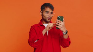 Mutlu Hintli genç adam akıllı telefon daktilo kullanıyor ve bağırıyor 