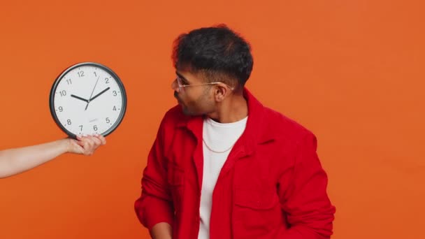 不安なインドの若者は 時計をチェックし 遅くまで仕事をし 遅刻期限を設けている アラビア人男性 スタジオオオレンジの背景で時間的隔離されることを心配 — ストック動画