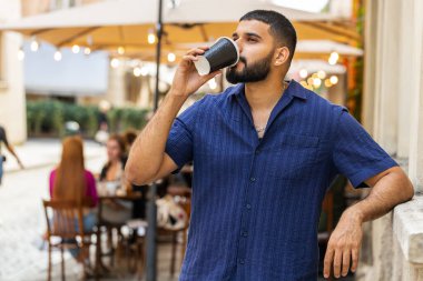 Mutlu sakallı Hintli adam sabah kahvesinin tadını çıkarıyor sıcak bir şeyler içiyor ve dışarıda gülümsüyor. Dinleniyorum, ara veriyorum. Şehirdeki Sunshine Caddesi 'nde yürüyen ve kahve içen bir adam. Dışarıdaki kasaba yaşam tarzları