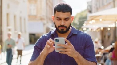 Mutlu gülümseyen sakallı Hintli adam internetteki sosyal medya uygulamalarını inceleyerek akıllı telefon yazıları yazıyor. Şehir caddesinde kameraya bakan bir turist. Kasaba yaşam tarzları