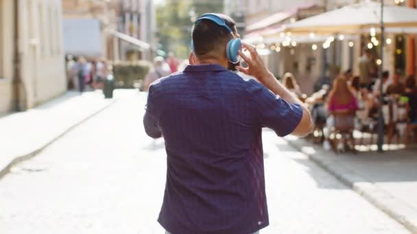 Achteraanzicht Van Indiaanse Man Toerist Draadloze Koptelefoon Wandelen Door Straat — Stockvideo