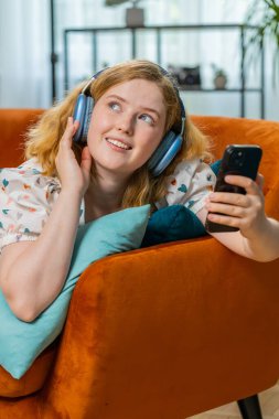 Kızıl saçlı, kablosuz kulaklıklı mutlu bir kadın evinde koltuğa uzanmış, en sevdiği enerjik disko dans müziğini dinliyor. İnsanlar hafta sonları boş zaman aktiviteleri yapar. Dikey