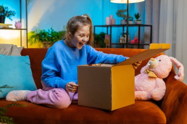 Kutuları açan mutlu küçük kız çocuğu. Gülümseyen Kafkas çocuk alışverişçisi, çevrimiçi dükkan müşterisi karton kutu açıyor eve hızlı posta yoluyla hediye alıyor.