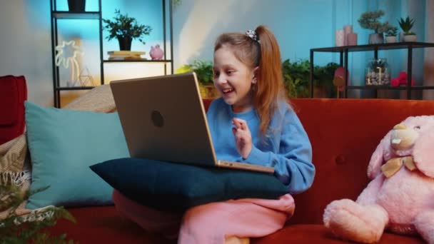 驚いたティーンエイジャーガールの子供はラップトップコンピュータを使用し 突然の勝利に衝撃を受け ゲームの勝利を祝い 宝くじのジャックポット 夜の自宅の部屋でオンラインショッピングを購入します — ストック動画