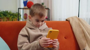 Akıllı telefon sosyal medya uygulamaları üzerinden rahatlama filmi izlerken mesajlaşan genç çocuk. Erkek ergen çocuk evde, oturma odasında koltukta cep telefonu kullanıyor.