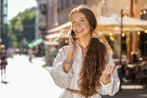 Teenager adult girl tourist having remote conversation communicate speaking by smartphone with friend talking on phone unexpected good news gossip walking in urban city street. Town lifestyles outdoor