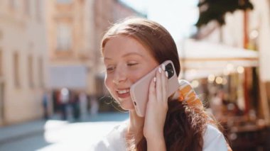 Yetişkin bir genç kız turist akıllı telefondan arkadaşlarıyla konuşuyor şehir sokaklarında beklenmedik bir şekilde iyi haber dedikodusu yapıyorlar. Şehir yaşam tarzları açık havada