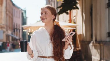 Mutlu kızıl saçlı genç kız sabah kahvesinin tadını çıkarıyor sıcak bir şeyler içiyor ve dışarıda gülümsüyor. Dinlenmeye çalışıyorum. Şehir merkezinde yürüyen bir kadın, gitmek için kahve içiyor. Dışarıdaki kasaba yaşam tarzları